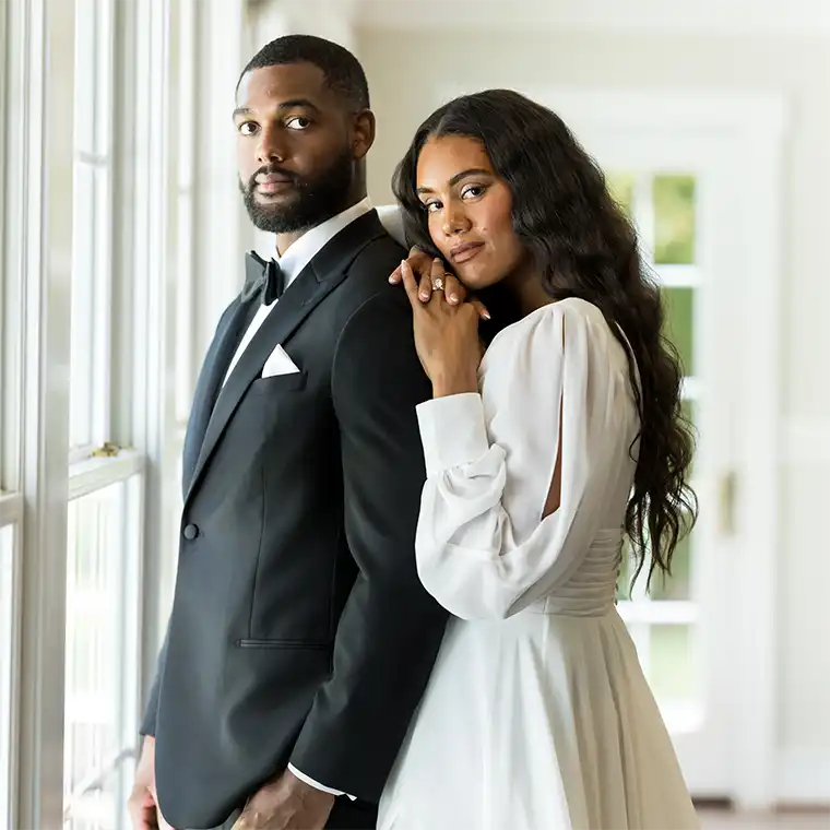 Groom in a black tuxedo with his bride in a white gown