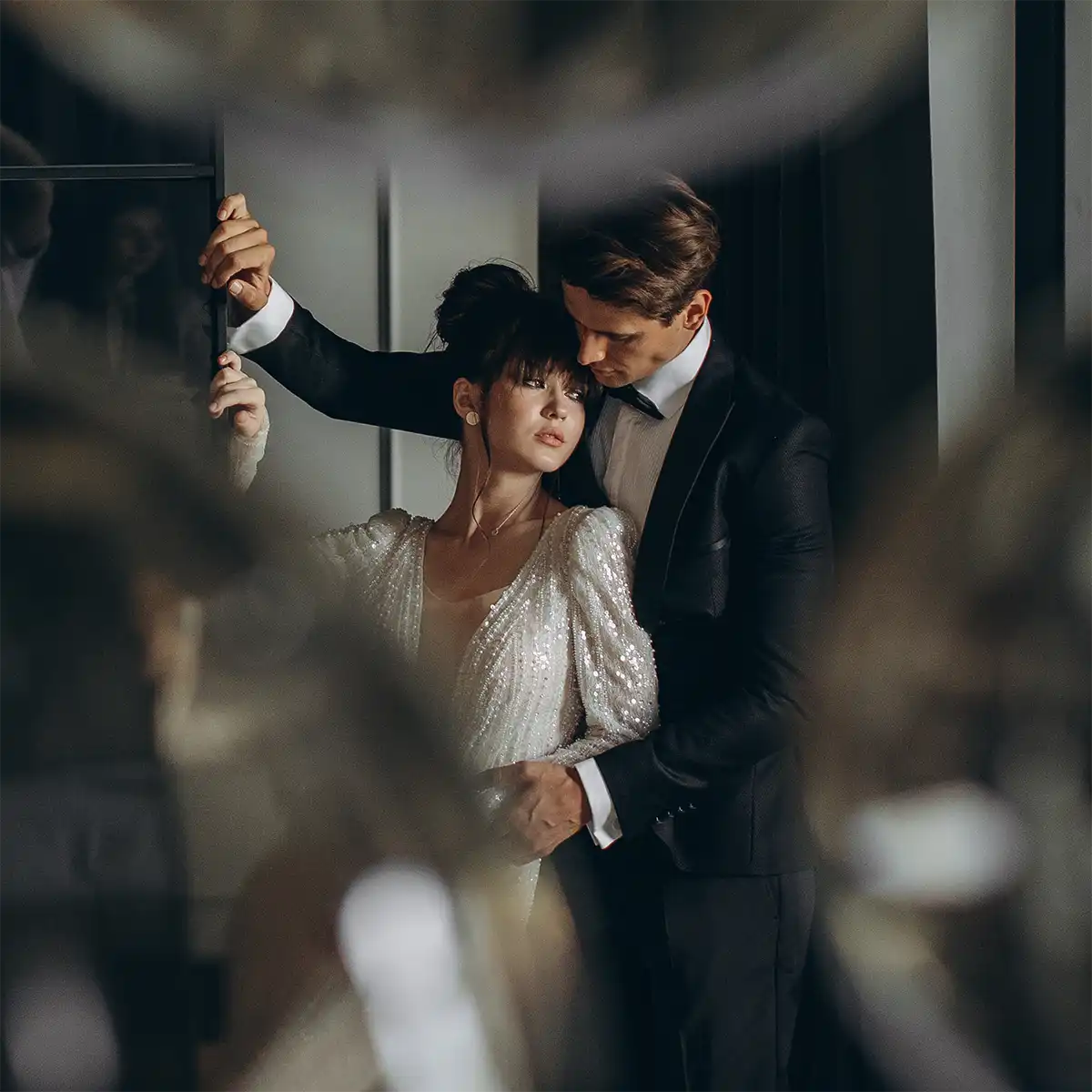 Bride and groom in a black tuxedo embracing in an elegant room